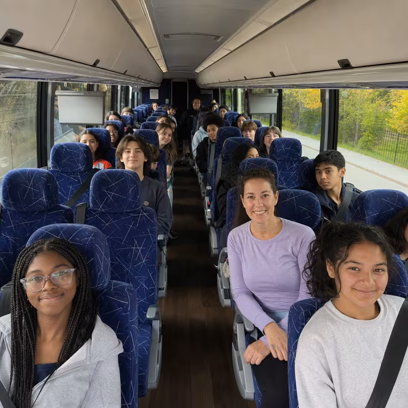 Group boarding a white charter bus for School Transportation transportation in St. Louis